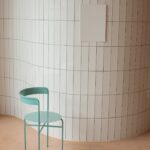 Chair near wall with ceramic tile and white placard