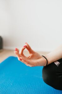 Crop unrecognizable woman meditating in Lotus pose at home