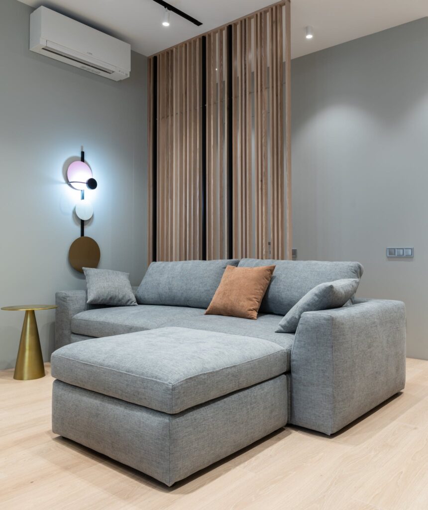 Interior of modern living room with sofa with pillows next to round table under conditioner